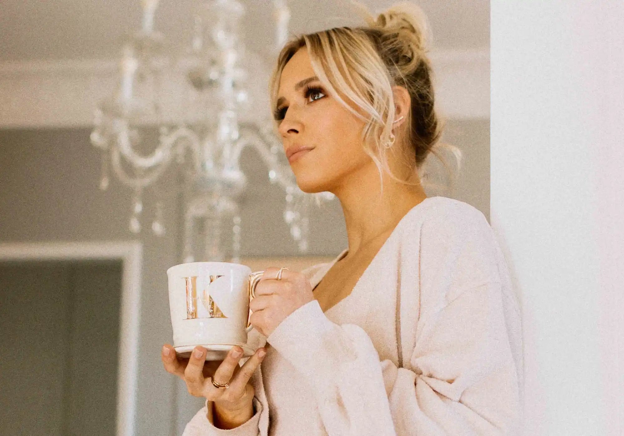 A person in a cozy white sweater holding a coffee mug.