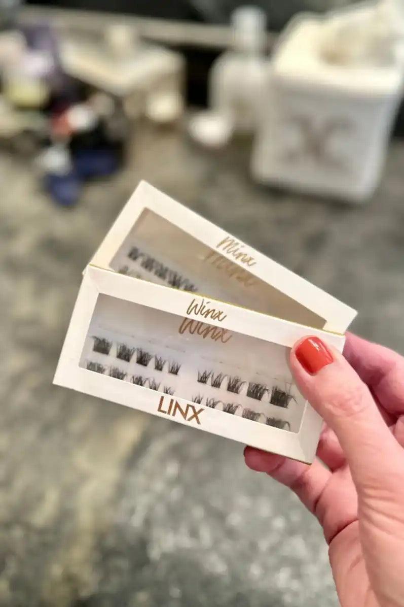 Two white tickets or passes labeled ’LINX’ being held by fingers with red nail polish.